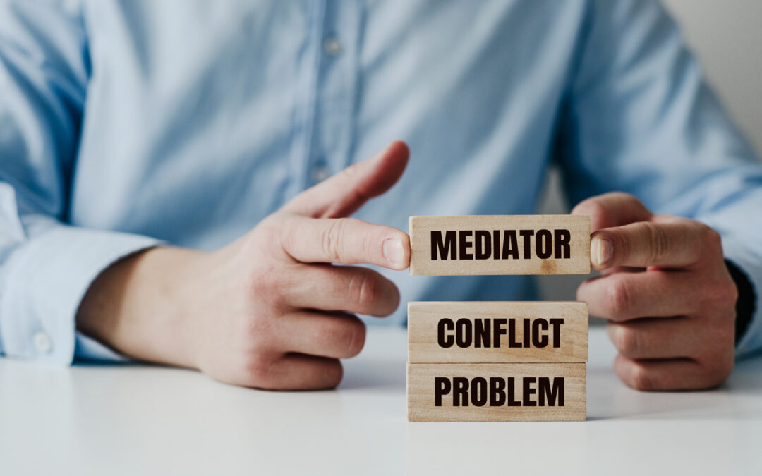 Businessman in a blue shirt arranges wooden jigsaw blocks with the word CONFLICT, MEDIATOR. Problem solving concept using a mediator, help during conflicts showing the benefits of divorce mediation in resolving conflict