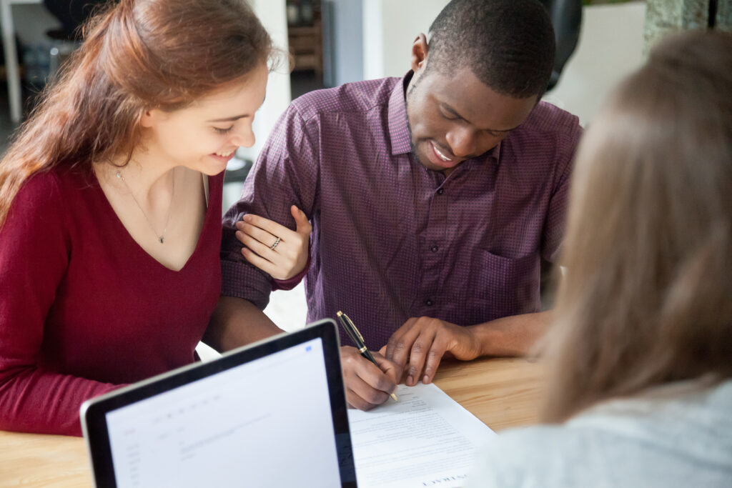 multi-racial couple signing a prenuptial agreement