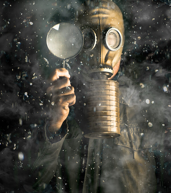 Creative portrait on a scientist wearing a gas mask while holding a magnifying glass to examine toxic words