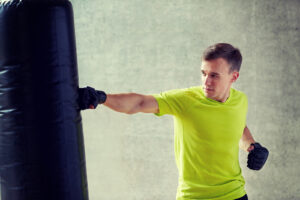man with boxing gloves hitting a punching bag in gym to reduce the stress of divorce